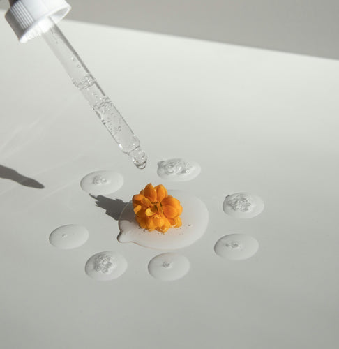 Serum dropped on orange flower laying in serums drops