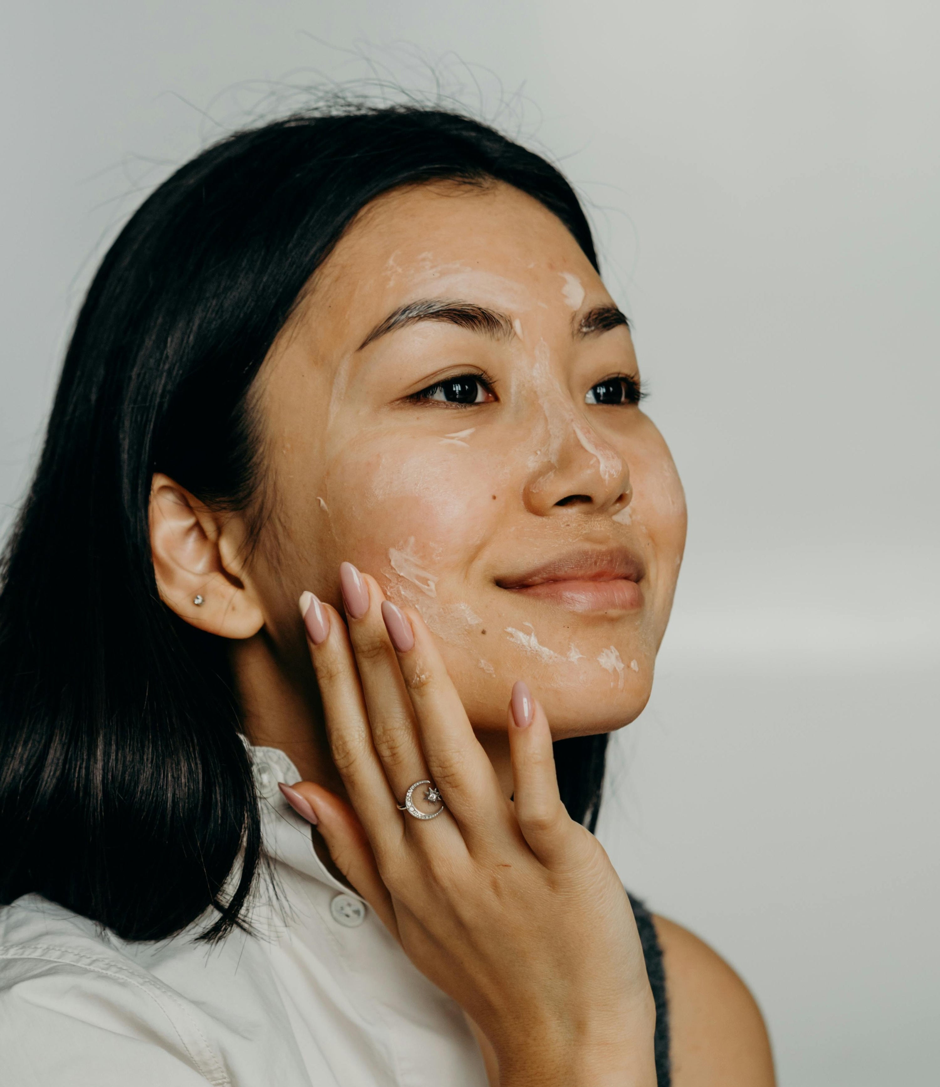 Woman applying skincare with left hand to face